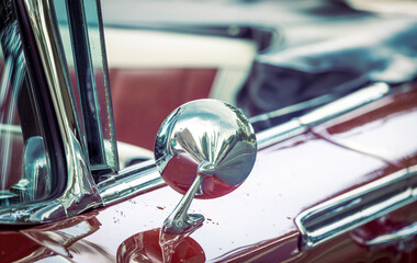 Close up shot of shiny side view mirror on a classic car