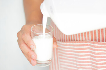 Chef hand of pouring pure milk drinks in bottles plastic in glass is naturally healthy foods placed on a wood deck in the background with copy space for text.