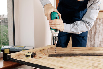 Handyman in blue uniform works with electricity automatic screwdriver. House renovation conception.