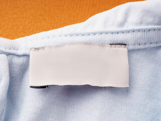 White blank label on the inside of the garment, on the neck, close-up. empty tag for sizes and...