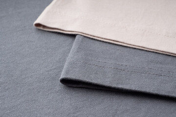 T-shirt sleeves close-up, copyspace, mock up, flat lai, top view. Ready-made T-shirt made of dark gray and beige thick cotton. Background of natural fabrics, texture. Elements of fashion clothing