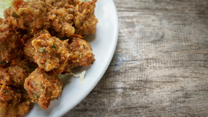 spicy fried pork and vergesteble on white disk with wood table, Asian style.
