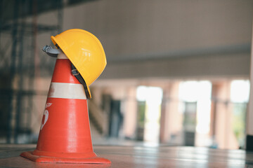 Orange plastic traffic cone and engineer's hat in the construction building