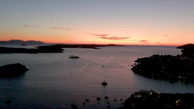 Flying over the harbour in sundown with some boats visible.