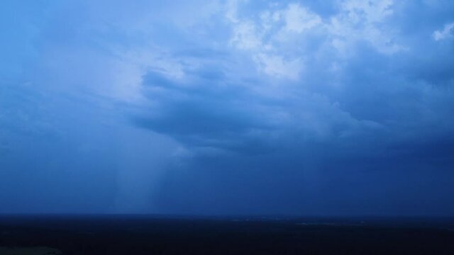 Beautiful aerial view of dramatic dark thunder storm clouds in summer evening, extreme thunderstorm with several spectacular lightning strikes deep in to the clouds, distant wide angle drone shot