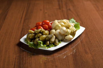 Pickled vegetables, pickles, tomatoes, patissons in a white plate on the table