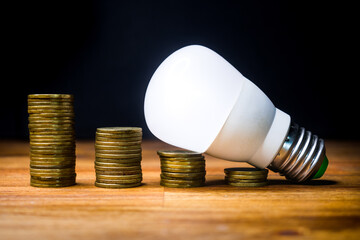 Stacks of coins with led spotlight above, electricity consumption, price reduction.
