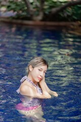 Woman in pink one piece swimsuit relax in swimming pool, summer vacation.