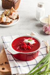 Delicious fresh red borscht, dark bread with lard and salt on kitchen table. 