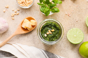Jar with fresh pesto sauce and ingredients on grunge background