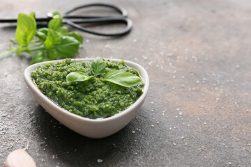Bowl with fresh pesto sauce on grunge background
