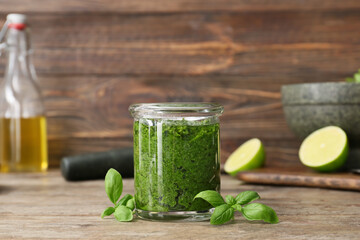 Jar with fresh pesto sauce on wooden background