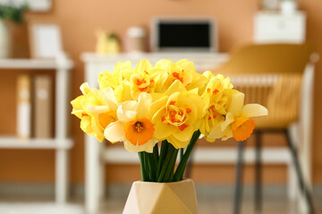 Vase with beautiful narcissus flowers in room