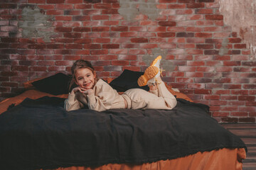 the girl is lying on the bed on the background of a brick wall