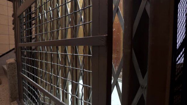 Detailed tracking shot of the metal grid protection, wooden door and old interior of an antique elevator