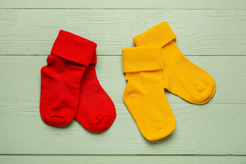 Baby socks on color wooden background, closeup