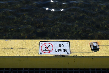 A wet no diving sign on a pier or jetty, warning of the danger posed by the shallow water bellow
