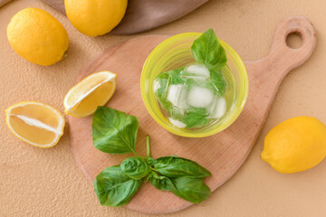 Glass of lemonade with basil on color background
