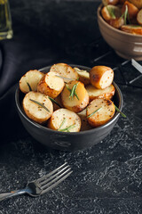 Bowl with baked potatoes on dark background