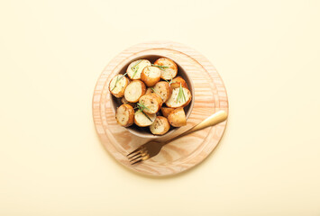 Bowl with baked potatoes on color background
