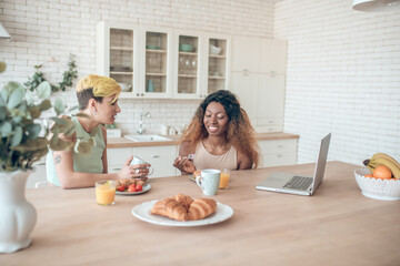 Obraz na płótnie Canvas Caucasian woman and dark skinned breakfast communicating