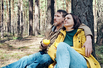 pensive middle-aged couple is resting in a coniferous forest. Local travel concept
