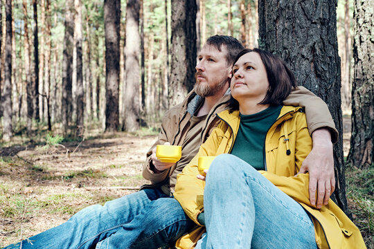 pensive middle-aged couple is resting in a coniferous forest. Local travel concept