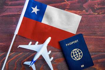 Flag of Chile with passport and toy airplane on wooden background. Flight travel concept 