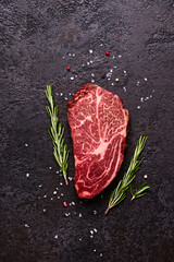 Fresh raw marbled beef rib eye steak and spices on black stone background