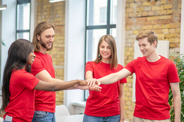 Fototapeta premium Joyful young volunteers showing togetherness gesture