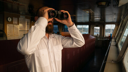 Navigational merchant officer watching with binocular during the sea passage.