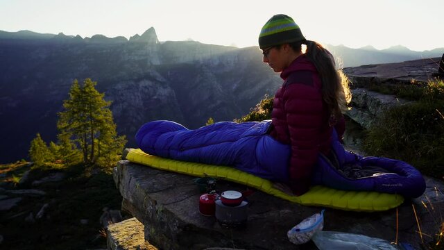 A woman at her bivouac on a beautiful morning in the mountains.
