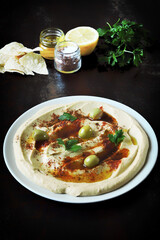 Hummus snack on a plate with olives and olive oil. Traditional Arabic appetizer.