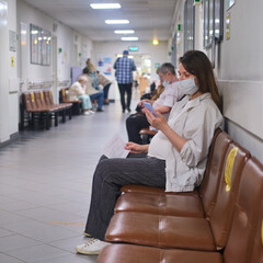 Pregnant woman with phone in hospital corridor with medical mask on face - Moscow, Russia, May 16,...