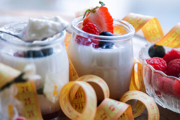 greek yogurt with strawberries and blueberries and measuring tape, diet and health concept