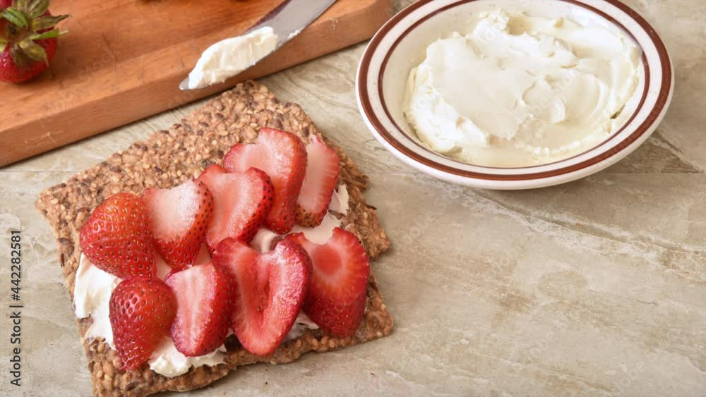 Wall mural topping a gluten free crispbread with cream cheese and strawberries stop motion animation