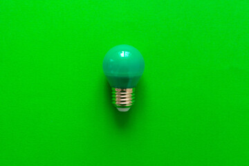 Light bulb on green paper background close up