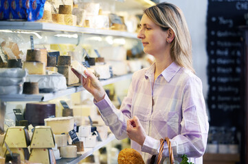Female Customer Shopping For Local Cheese In Delicatessen Food Shop