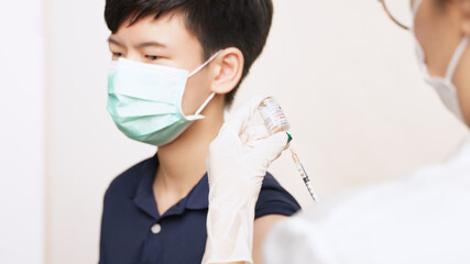 COVID 19 Vaccines for kids and teenager Issue. A smart asian teen boy with medical face mask about to get a vaccine shot at the hospital. Safe, Authorized, Back to school, Insurance, Healthcare.