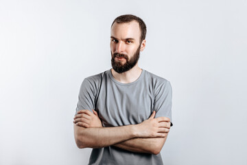 Portrait of a handsome brutal brunette serious man on a white background with crossed arms. The person will soon become the owner of a startup business.