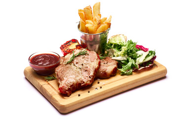 Grilled roated beef steaks, potato, sauce and salad on wooden cutting board