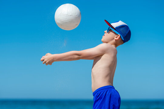 Young boy playing volleyball on beach. Summer sport concept. - Powered by Adobe