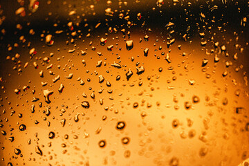 Water droplets on window on golden background.