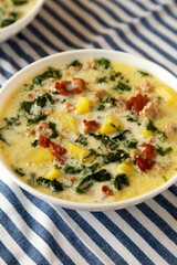 Homemade Zuppa Toscana with Kale and Bread in a white bowl, side view.