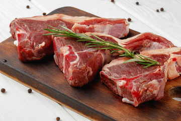 Raw meat ribs on wooden board on white background