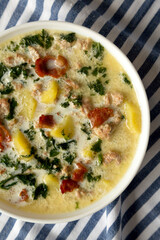 Homemade Zuppa Toscana with Kale and Bread in a white bowl, top view. Flat lay, overhead, from above.