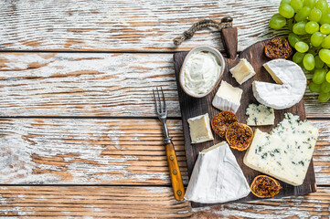 Cheese board with brie, Camembert, Gorgonzola and blue creamy cheese. White wooden background. Top view. Copy space