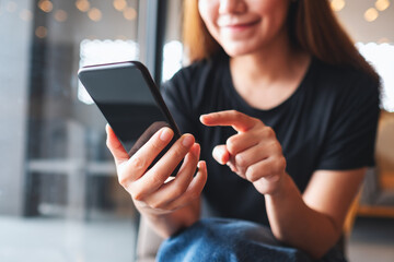 Closeup image of a beautiful young asian woman holding and using mobile phone