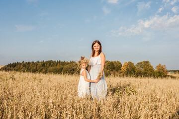 Young mother and daughter stand in field.