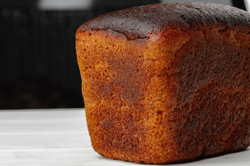 Loaf of rye bread on white wooden table